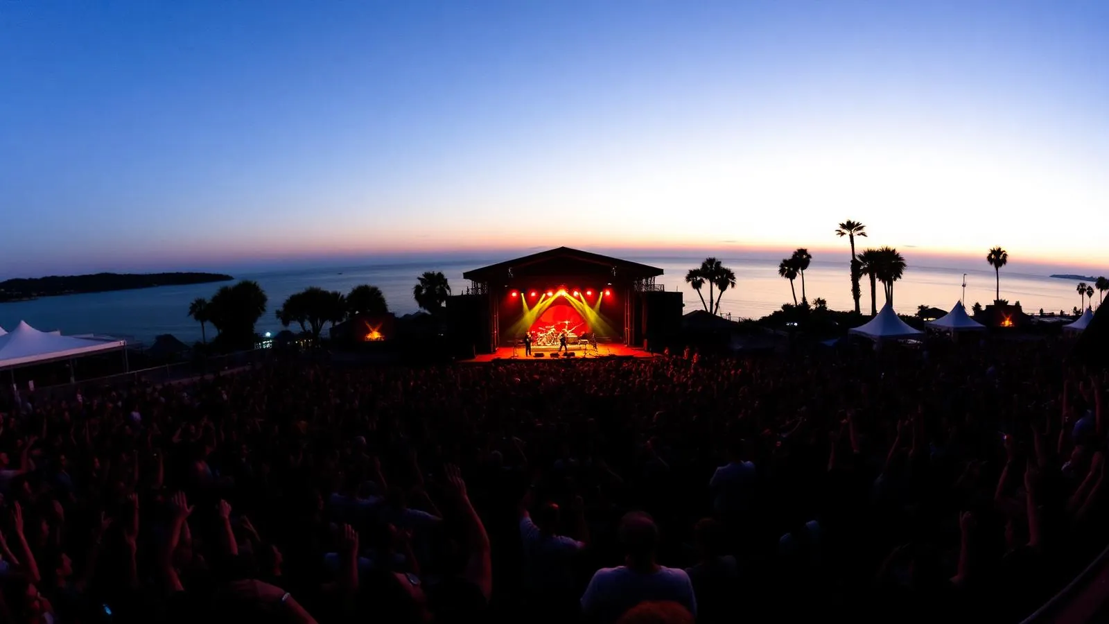 Crowd at an outdoor bayside concert in San Diego at dusk with stage lights