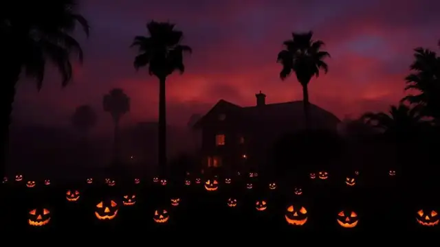Glowing jack-o-lanterns and a haunted house silhouette under palm trees on a foggy Halloween night in San Diego