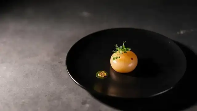 Elegant Michelin-style fine dining course on a black plate at a San Diego tasting menu restaurant