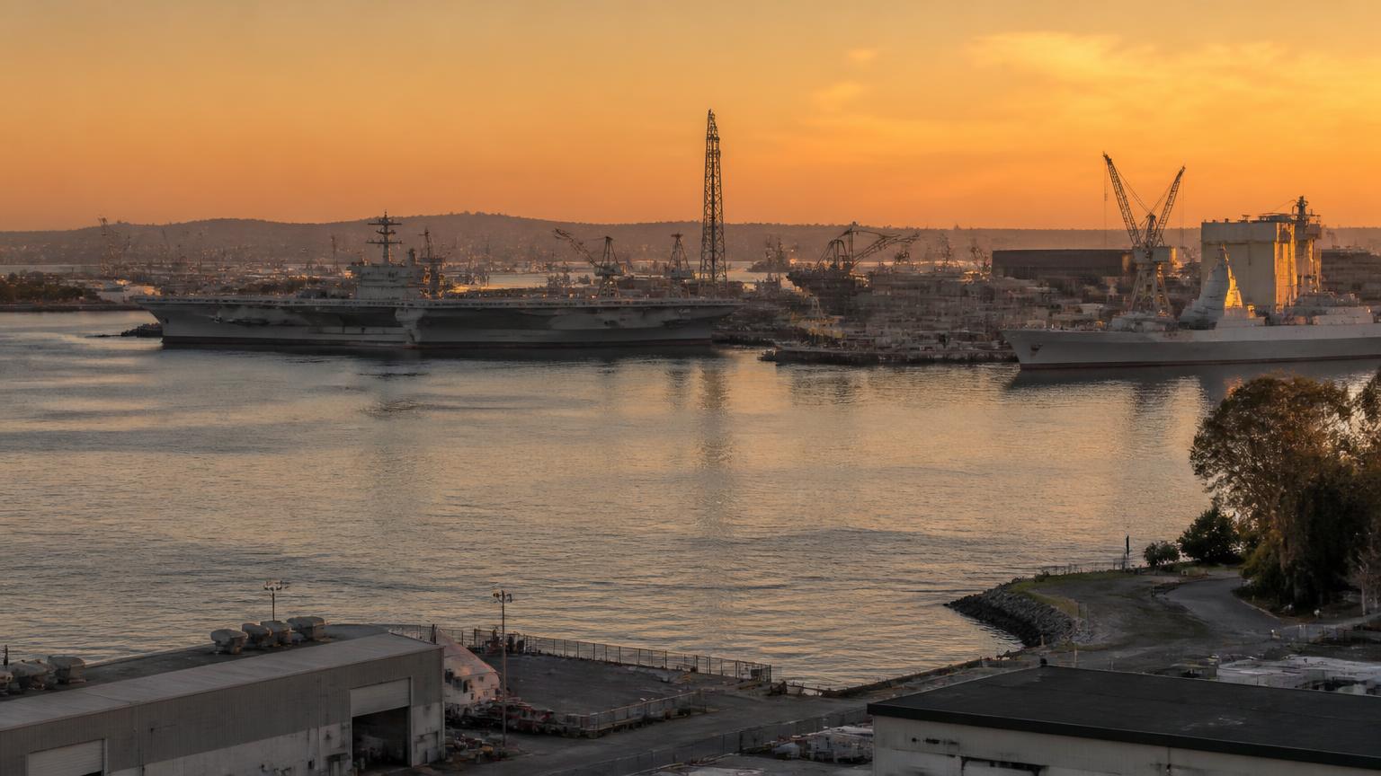 San Diego Bay shipyard at golden hour with naval vessels and shipbuilding cranes along the industrial waterfront