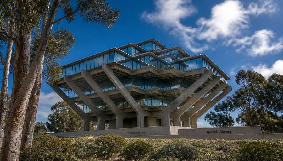 The Brutalist concrete and glass Geisel Library at UC San Diego framed by eucalyptus trees under a bright blue sky