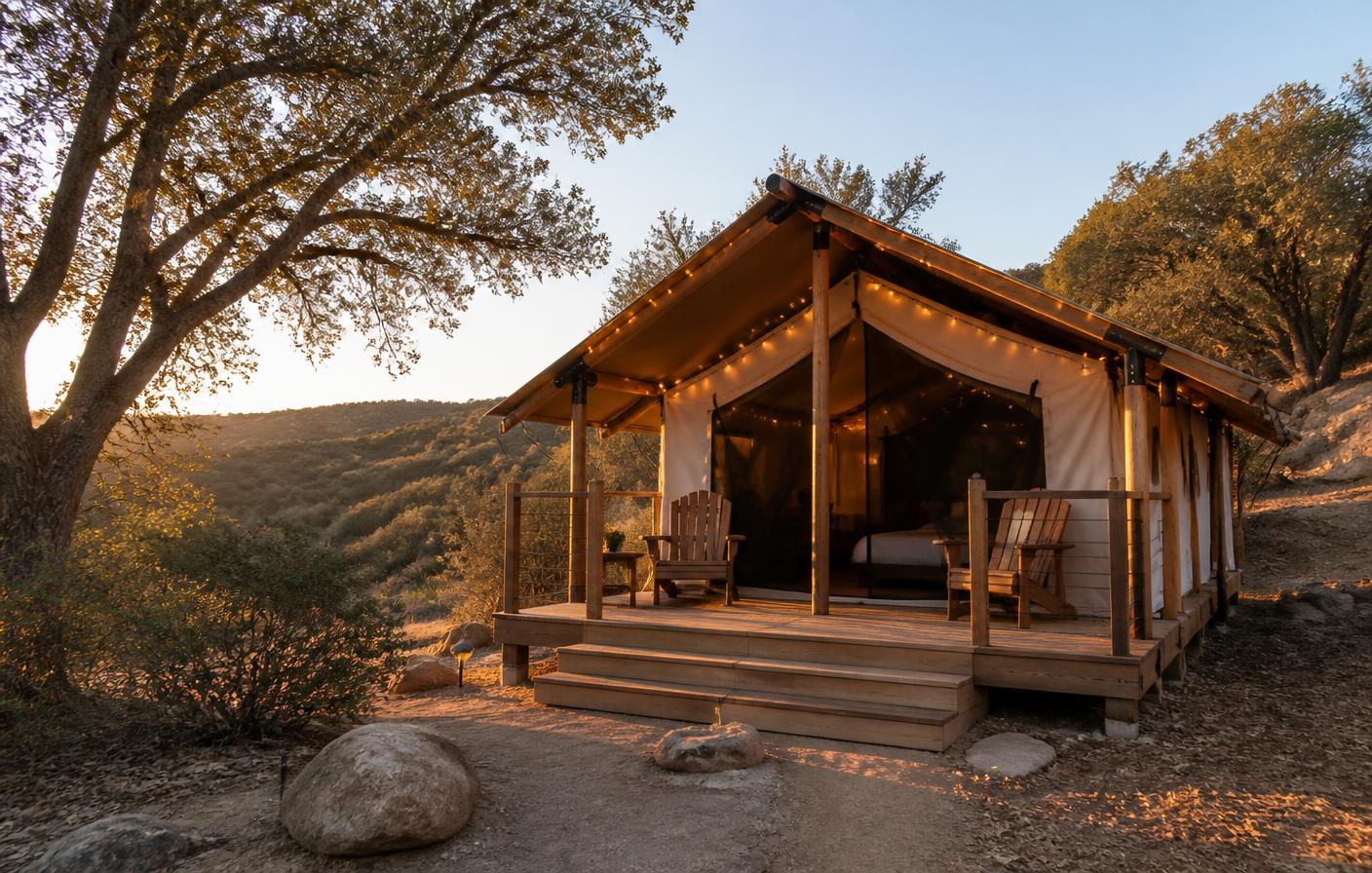 Canvas safari glamping tent with string lights, wooden deck, and Adirondack chairs on an oak-covered San Diego County hillside at golden hour