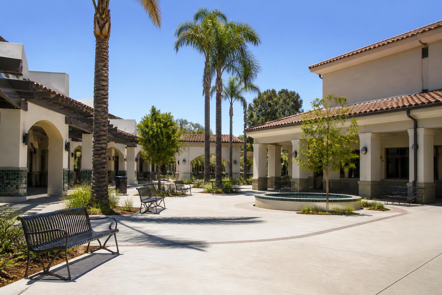 Sunny Southern California school campus courtyard with stucco buildings, covered walkways and palm trees