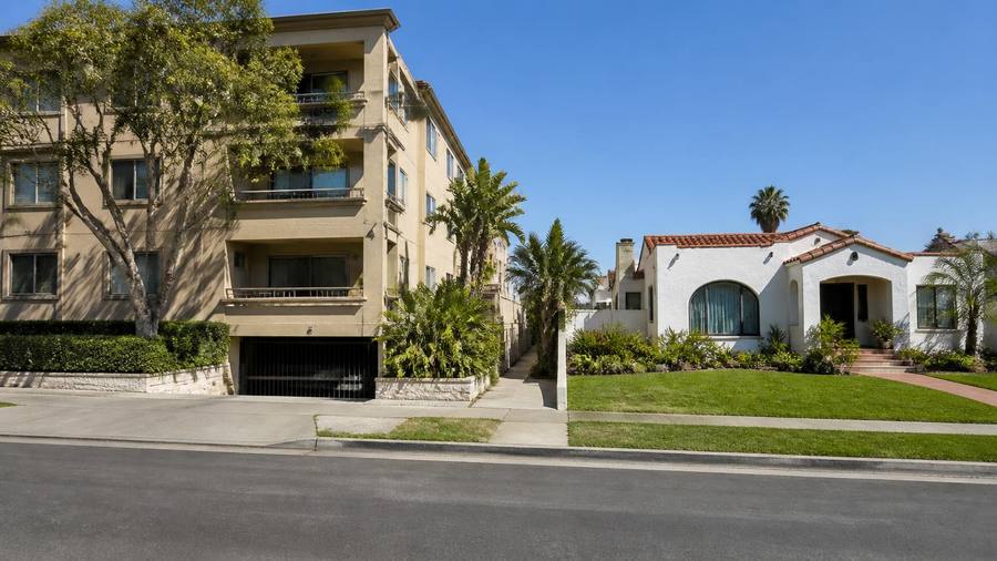 San Diego street with an apartment building on one side and a single-family stucco house with a lawn on the other