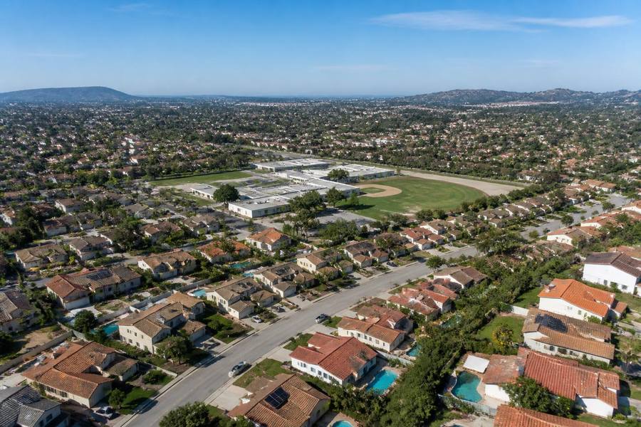 Aerial view of a San Diego suburban neighborhood with tile-roof homes and a school campus with sports field