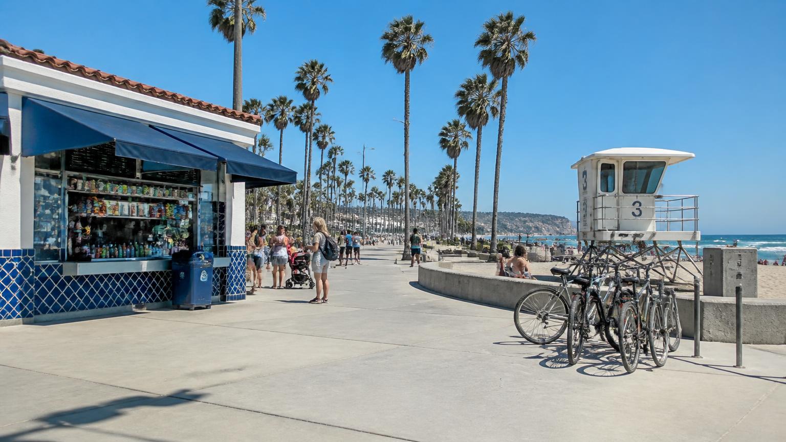 Beach boardwalk concession stand and lifeguard tower on a sunny summer day in San Diego with bikes parked nearby