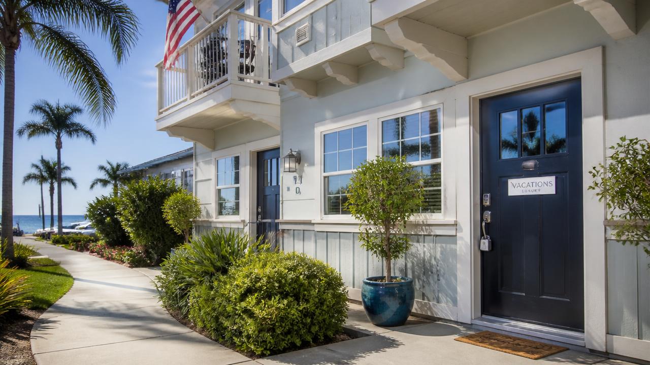 Beach-adjacent San Diego vacation rental duplex with a key lockbox on the front door and palm trees